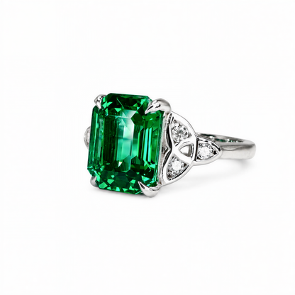 A stunning ring featuring a large, vibrant green gemstone set in a silver band, with smaller diamonds adorning the sides.
