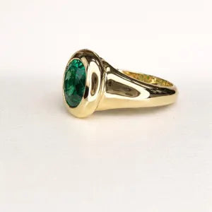 A gold ring with a large oval-shaped green gemstone set in the center.