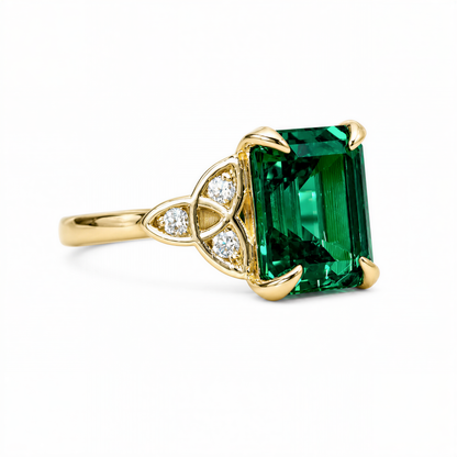 A gold ring with a large, green gemstone, possibly a diamond, set in the center.