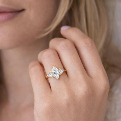 A close-up of a person's hand wearing a gold engagement ring with a large diamond center stone surrounded by smaller diamonds.