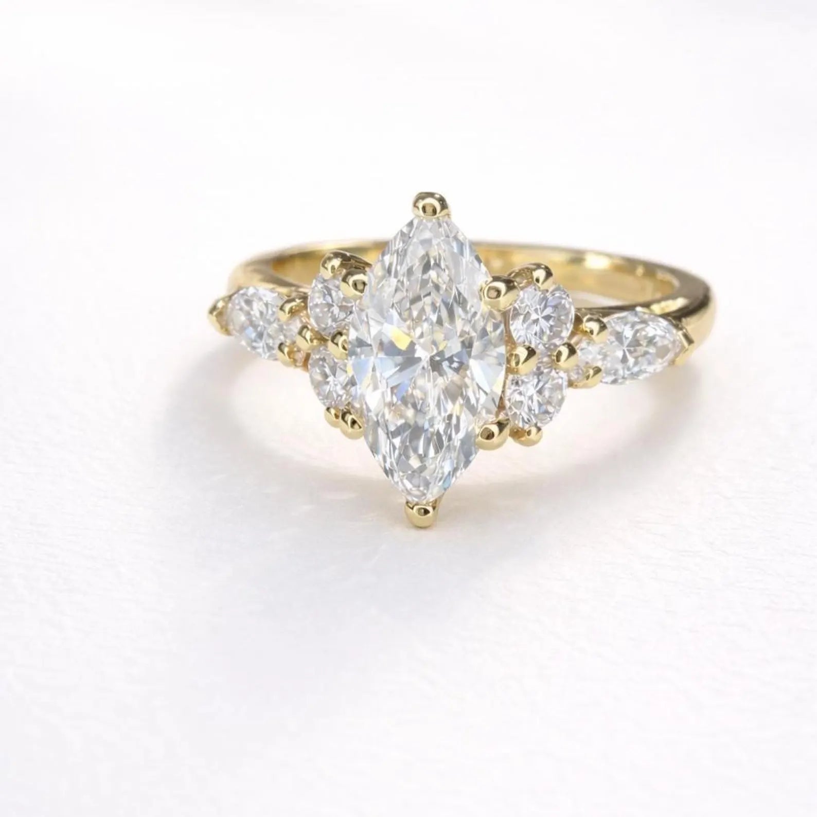 A gold engagement ring with a large central diamond surrounded by smaller diamonds on either side.