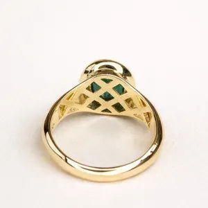 A gold ring with a green gemstone set in the center, showcasing the intricate design and craftsmanship of the piece.