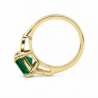 A gold ring with a large green gemstone, possibly an emerald, set in the center.
